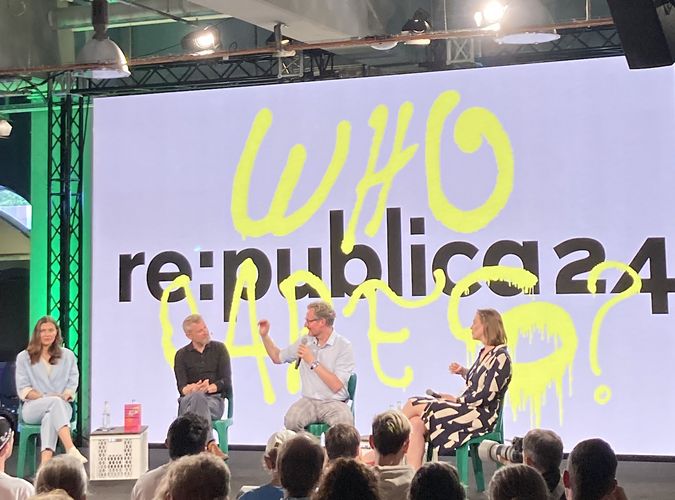 Das Bild zeigt eine Szene während eines Vortrags auf der re:publica 2024. Auf der Leinwand hinter der Bühne ist das Motto der Konferenz zu lesen: Who cares?