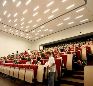 Blick in die Gesichter neugieriger Kinder sitzen in den Reihen eines sehr großen Hörsaals. 