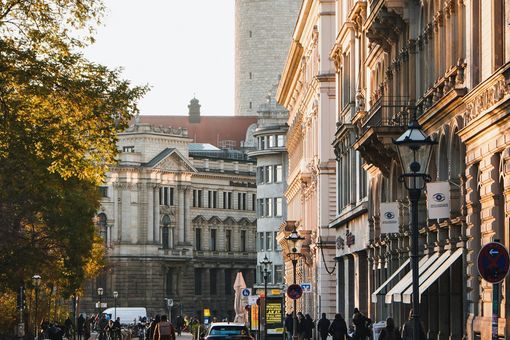 Das Foto zeigt einen Blick in eine Straße zwischen großen und alten Gebäuden. 